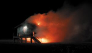An elevated house on fire in the night.